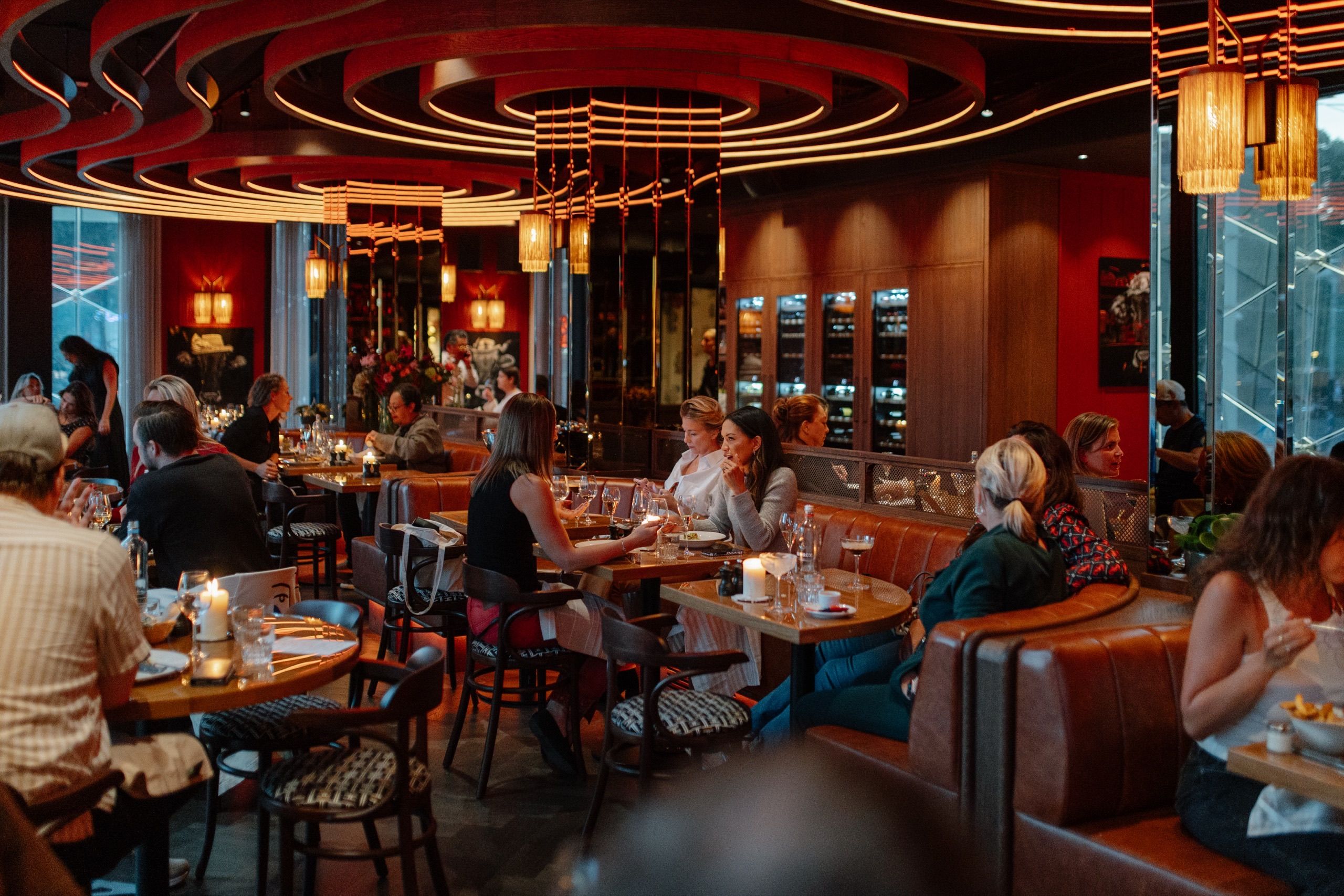 Warm rood licht en lantaarns in de Bistro, gasten aan tafels bij het raam