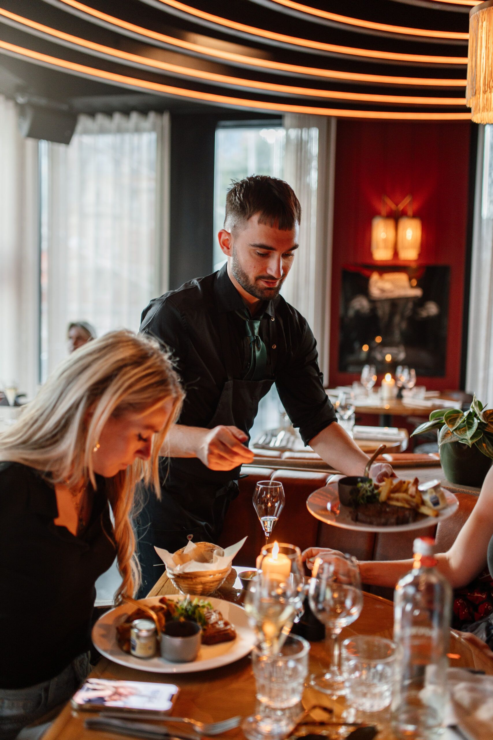 Waiter serving a dish to guests at a candlelit table
