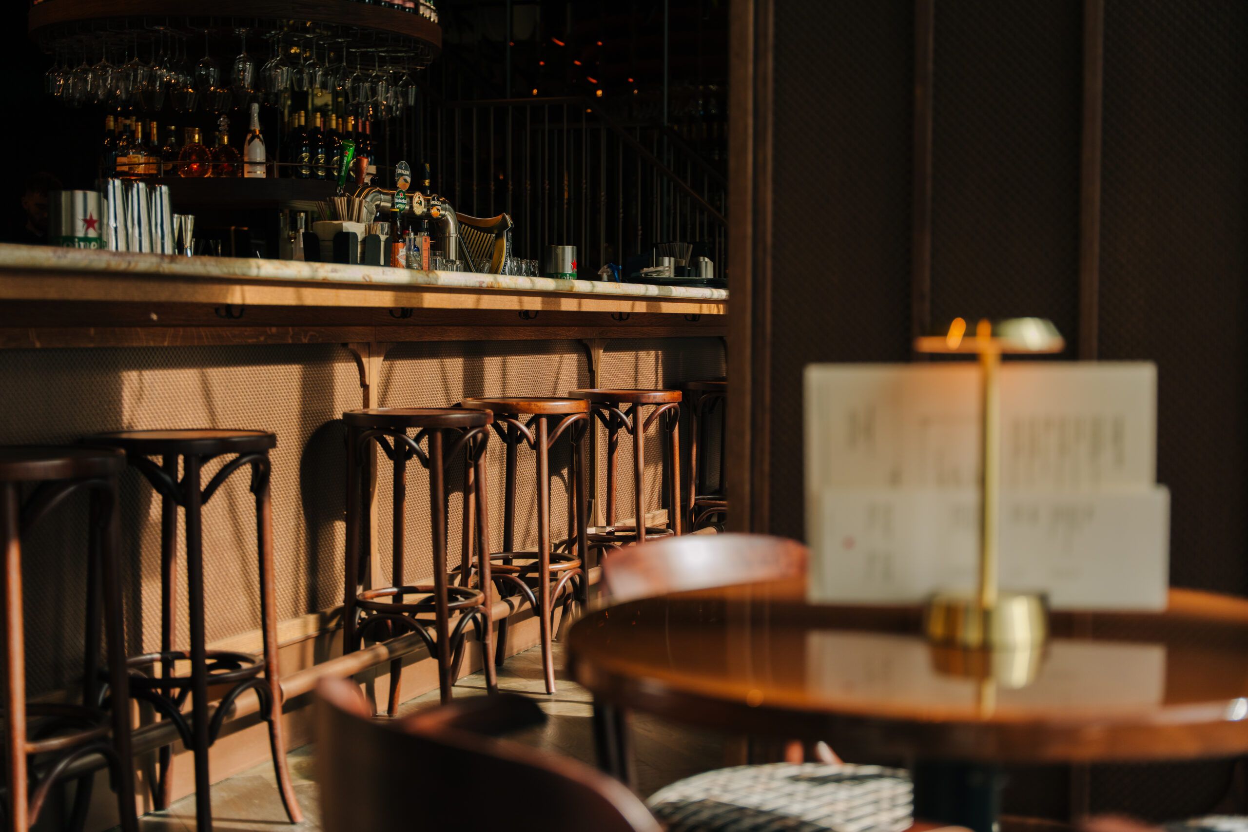 The bar with wooden bar stools, a brass table lamp in the foreground