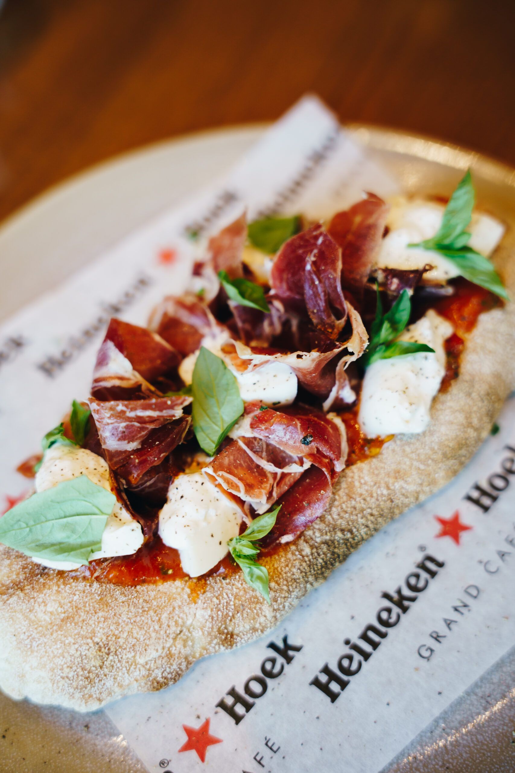 Flatbread with cured ham, mozzarella and basil on Heineken Hoek paper
