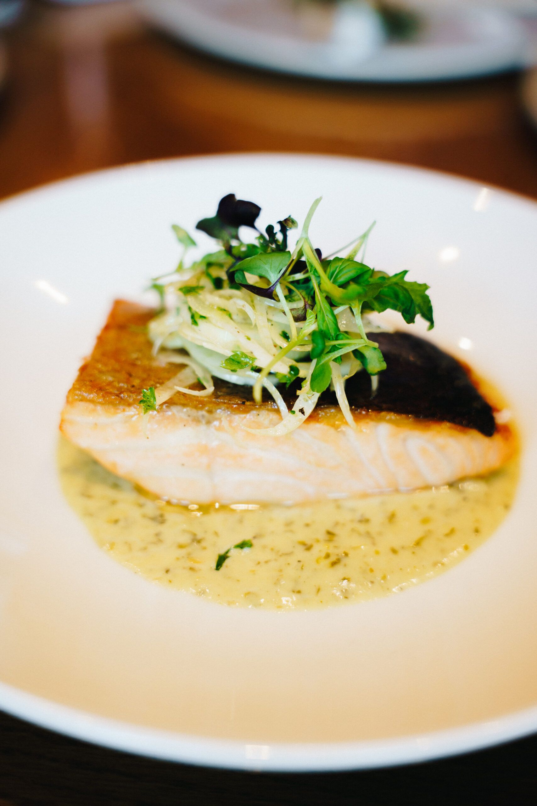Crispy-skinned salmon fillet topped with fennel and cress in a herb sauce
