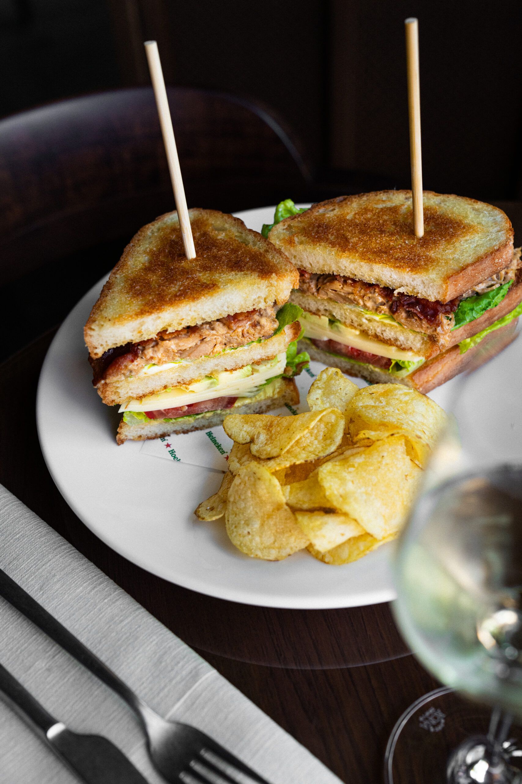 Club sandwich on skewers with crisps on a white plate